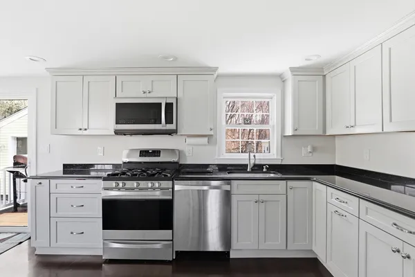 a kitchen with stainless steel appliances a stove a sink and white cabinets