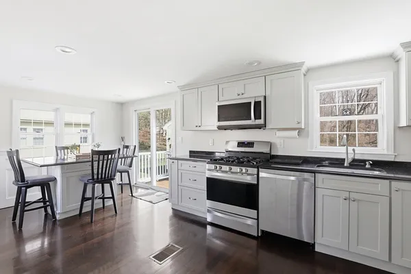 a kitchen with stainless steel appliances granite countertop a stove a sink a microwave a dining table and chairs