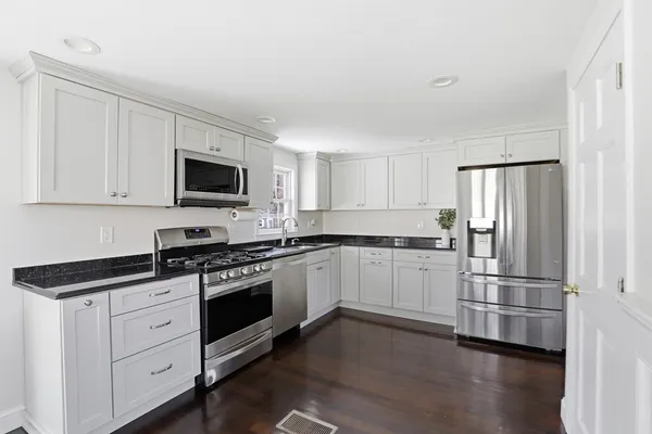 a kitchen with granite countertop a refrigerator stove and microwave