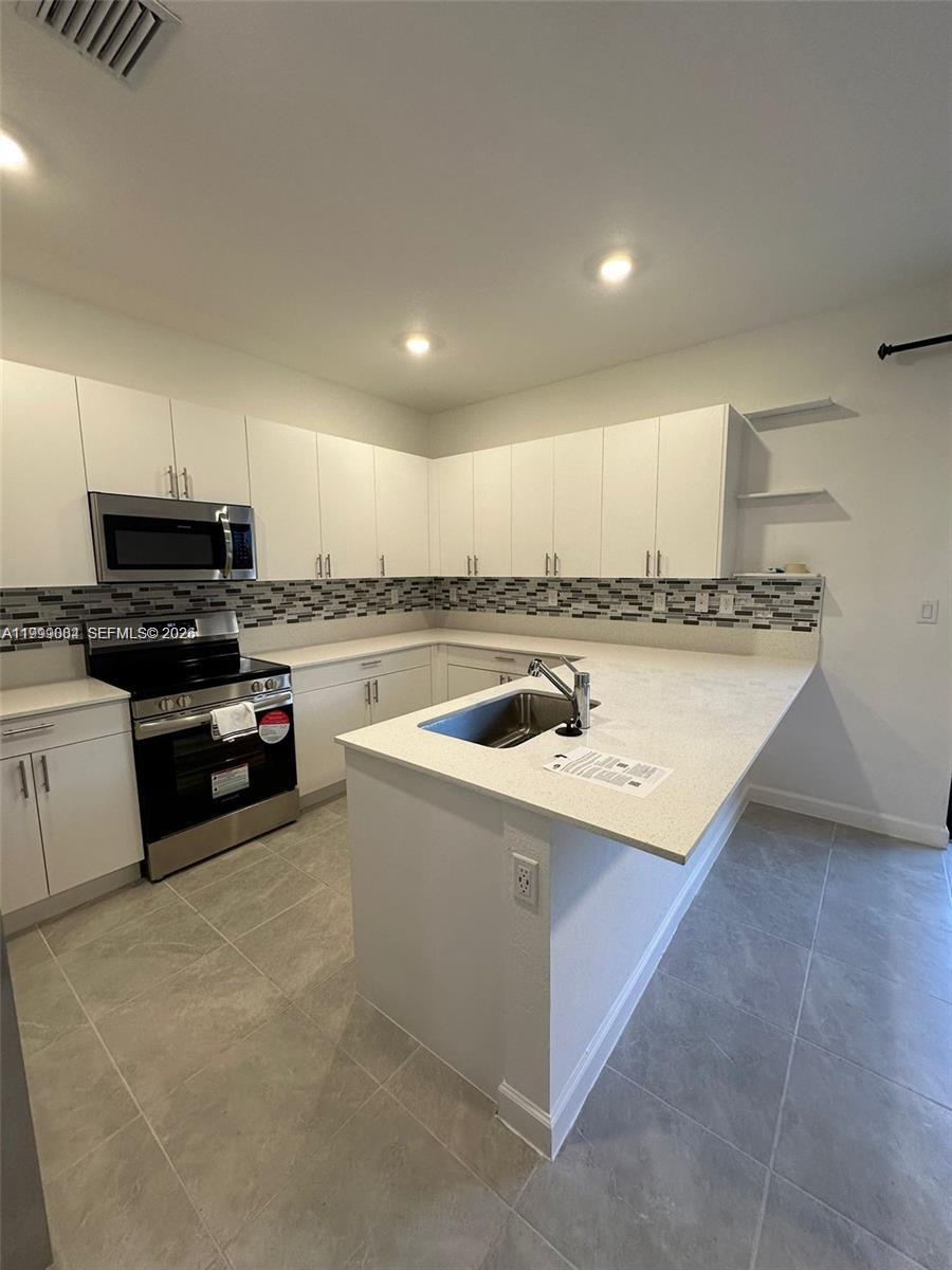 12868 Southwest 232nd Terrace Homestead, FL 33032 - Photo 13 of 48 a kitchen with a stove a sink and a microwave