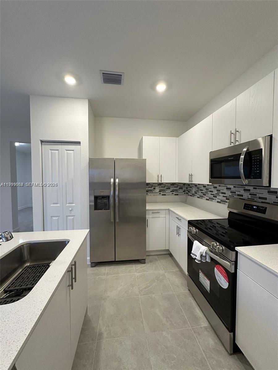 12868 Southwest 232nd Terrace Homestead, FL 33032 - Photo 14 of 48 a kitchen with granite countertop a sink a counter space stainless steel appliances and cabinets