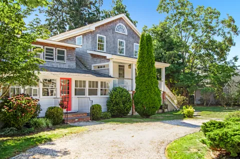 a front view of a house with a yard and potted plants