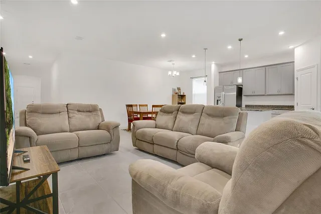 a living room with furniture white walls and kitchen view