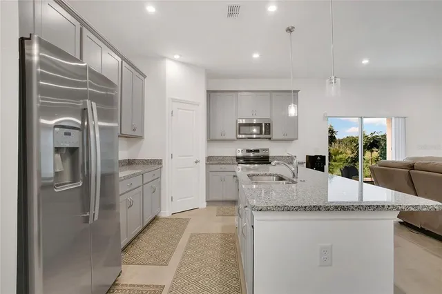 a large kitchen with kitchen island a large counter top stainless steel appliances and cabinets