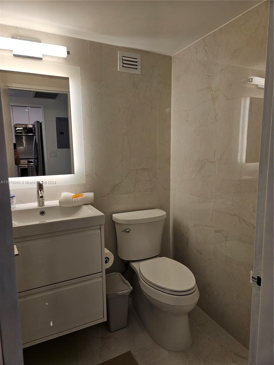 5601 Collins Avenue, Unit 1605 Miami Beach, FL 33140 - Photo 9 of 19 a bathroom with a toilet a sink and mirror