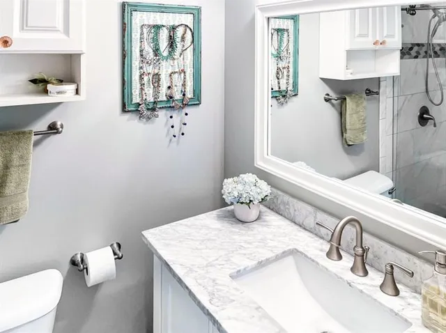 a bathroom with a granite countertop sink a toilet and a mirror