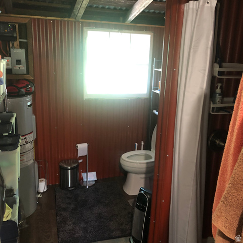 13581 13581st Huntsville, UT 84317 - Photo 5 of 11 Bathroom featuring corrugated metal walls, a white framed window, a standard white toilet, wood-finish flooring, and a stand-up shower with a white curtain