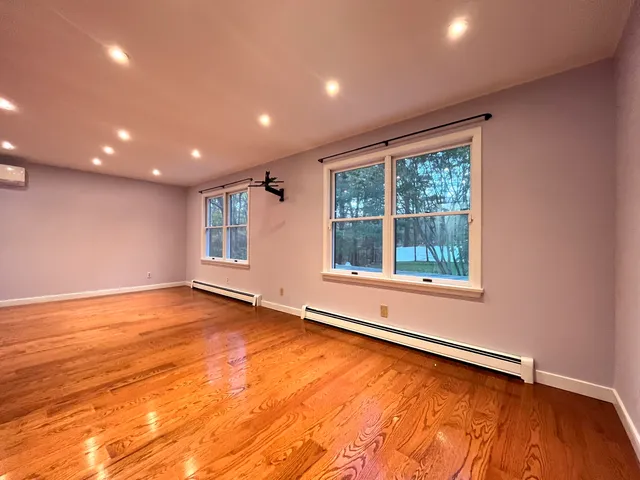an empty room with wooden floor cabinet and windows
