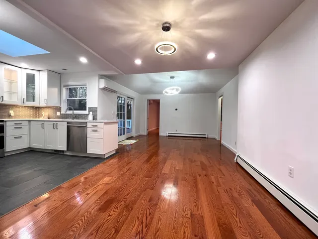 a view of an empty room with wooden floor and windows