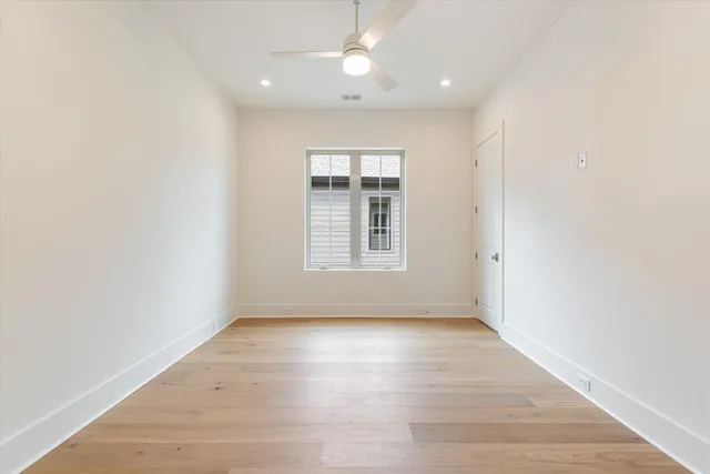 an empty room with wooden floor cabinet and windows