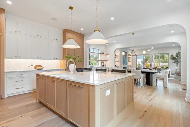 a kitchen with kitchen island granite countertop a stove a sink a center island and wooden floor