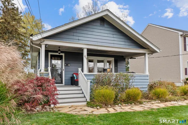 a view of a house with potted plants and a large tree
