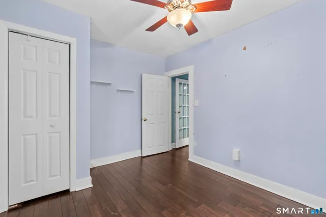 an empty room with wooden floor chandelier fan and windows