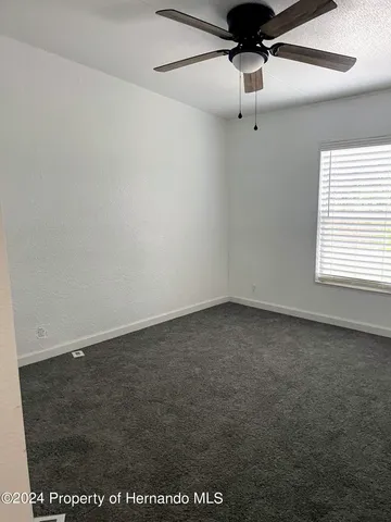 a view of a room with a ceiling fan and window