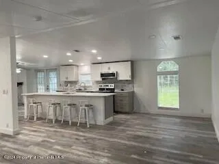 a large white kitchen with kitchen island granite countertop a stove top oven a sink and dishwasher with wooden floor