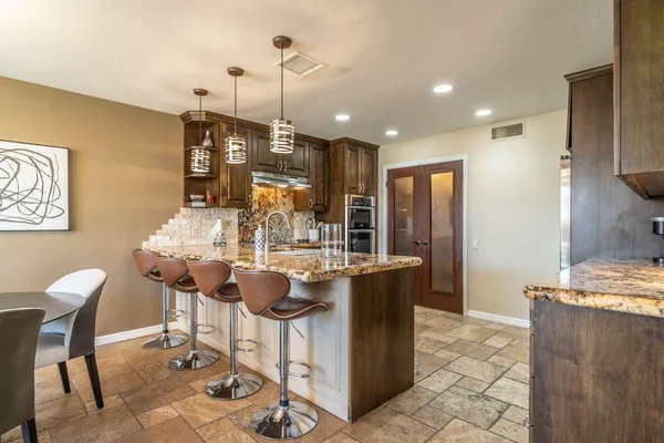 a kitchen with granite countertop a refrigerator and cabinets