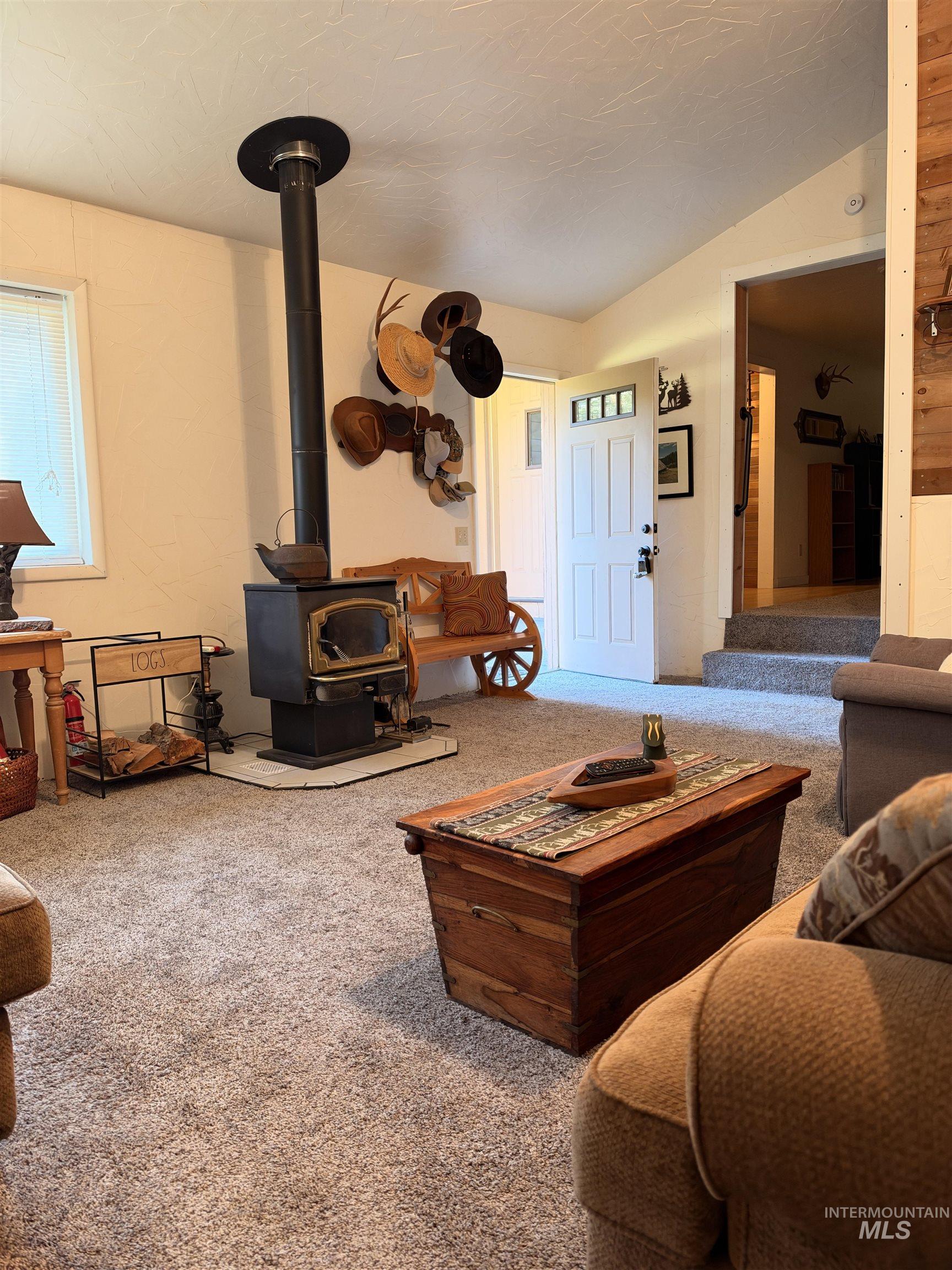 687 Big Cedar Road Kooskia, ID 83539 - Photo 20 of 37 Freestanding wood-burning stove with hearth, light-toned wall finishes, and textured carpeting