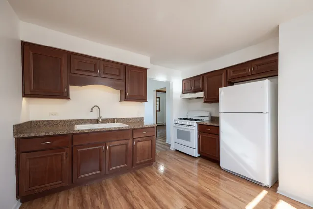 a kitchen with stainless steel appliances granite countertop a refrigerator a sink dishwasher a stove with wooden floor and cabinets