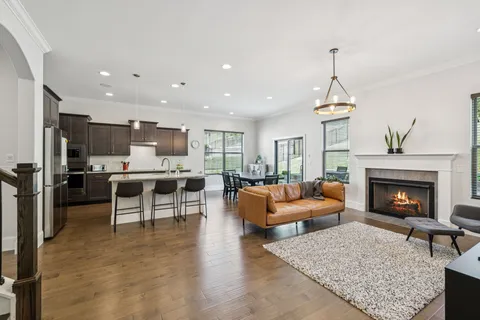 a living room with furniture kitchen view and a wooden floor