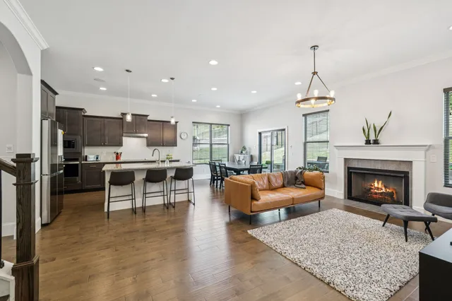 a living room with furniture kitchen view and a wooden floor