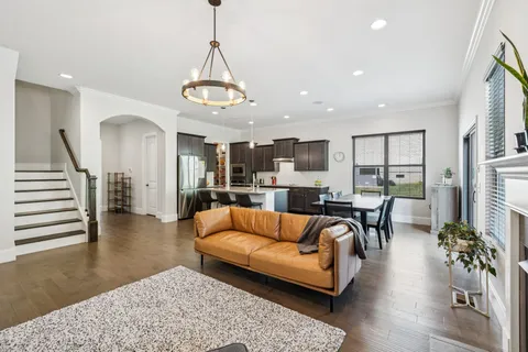 a living room with furniture kitchen view and a wooden floor