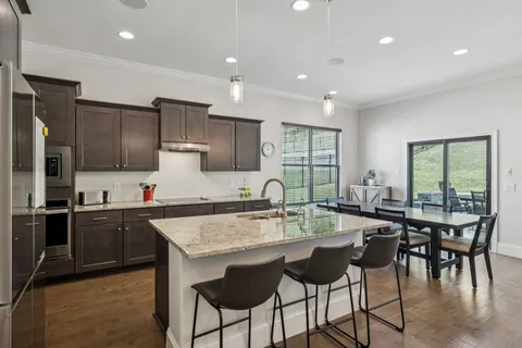 a kitchen with stainless steel appliances granite countertop table chairs sink and cabinets