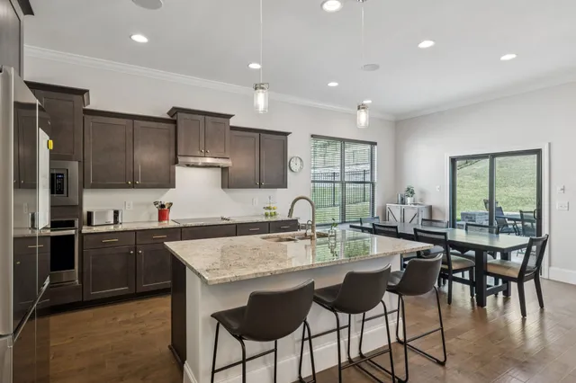 a kitchen with stainless steel appliances granite countertop table chairs sink and cabinets