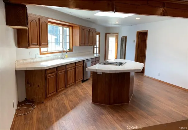 a room with kitchen island granite countertop wooden floors and a sink