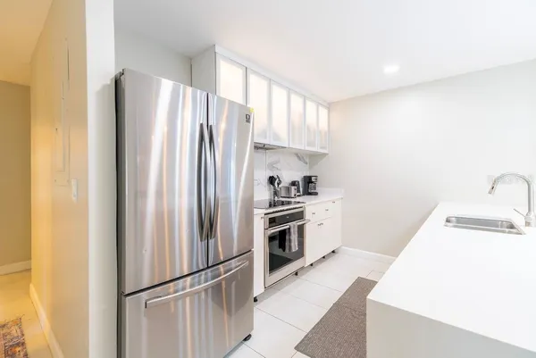 a large white kitchen with a sink and dishwasher a stove with wooden floor