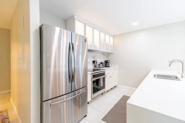 a large white kitchen with a sink and dishwasher a stove with wooden floor