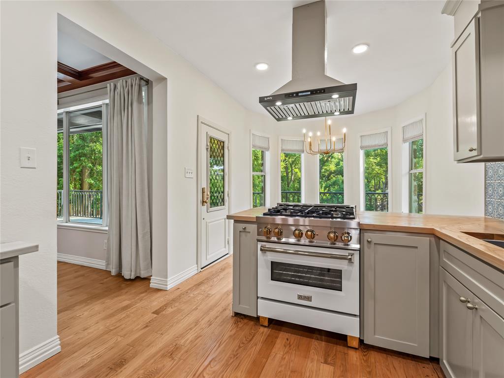 153 Meadowcreek Road Coppell, TX 75019 - Photo 13 of 35 Kitchen with high end stove, island exhaust hood, gray cabinets, wood counters, and a peninsula