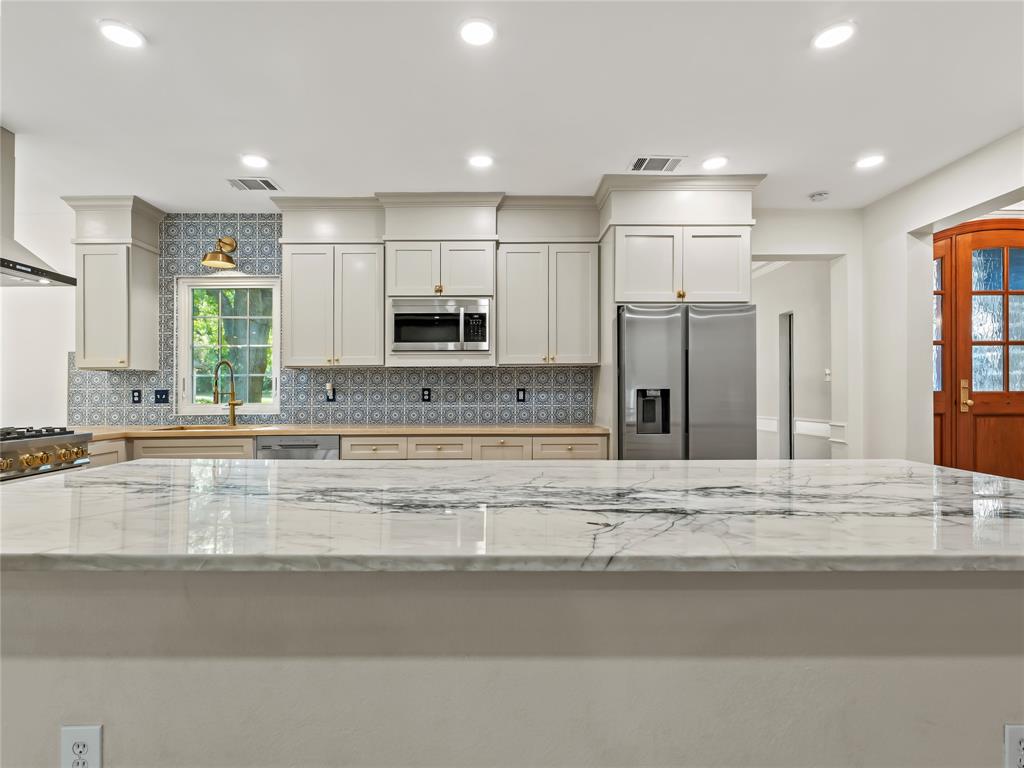 153 Meadowcreek Road Coppell, TX 75019 - Photo 14 of 35 Kitchen featuring stainless steel appliances, decorative backsplash, light stone counters, recessed lighting, and white cabinetry