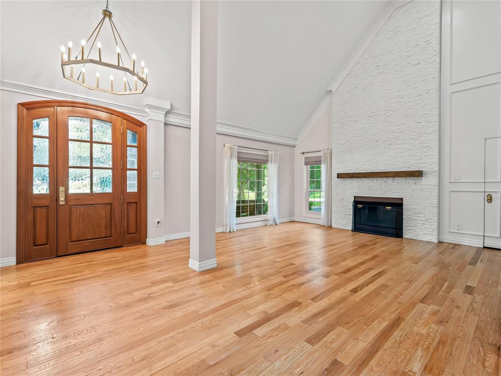 153 Meadowcreek Road Coppell, TX 75019 - Photo 6 of 35 Foyer featuring a fireplace, vaulted ceiling, light wood-style floors, and a chandelier