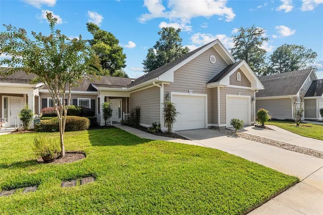 a view of a yard in front of a house with plants and large tree