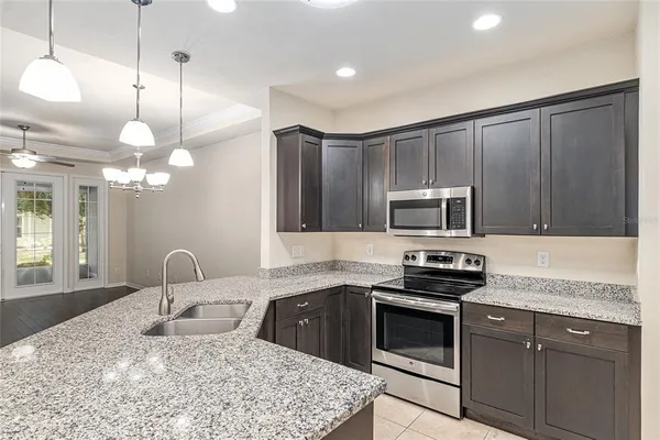 a kitchen with kitchen island granite countertop a sink stainless steel appliances and cabinets