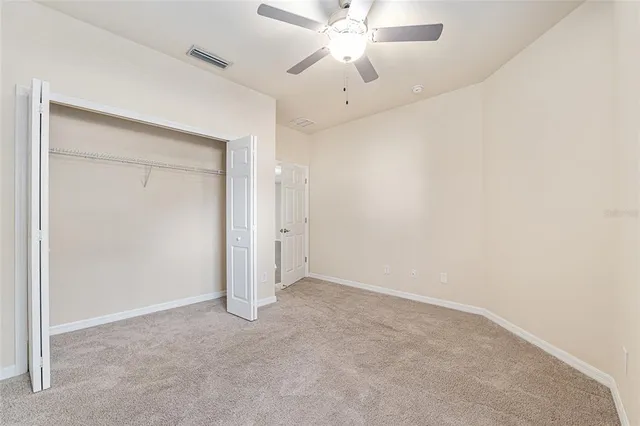 an empty room with a chandelier fan and closet area