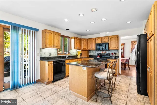a kitchen with stainless steel appliances kitchen island granite countertop a refrigerator and cabinets