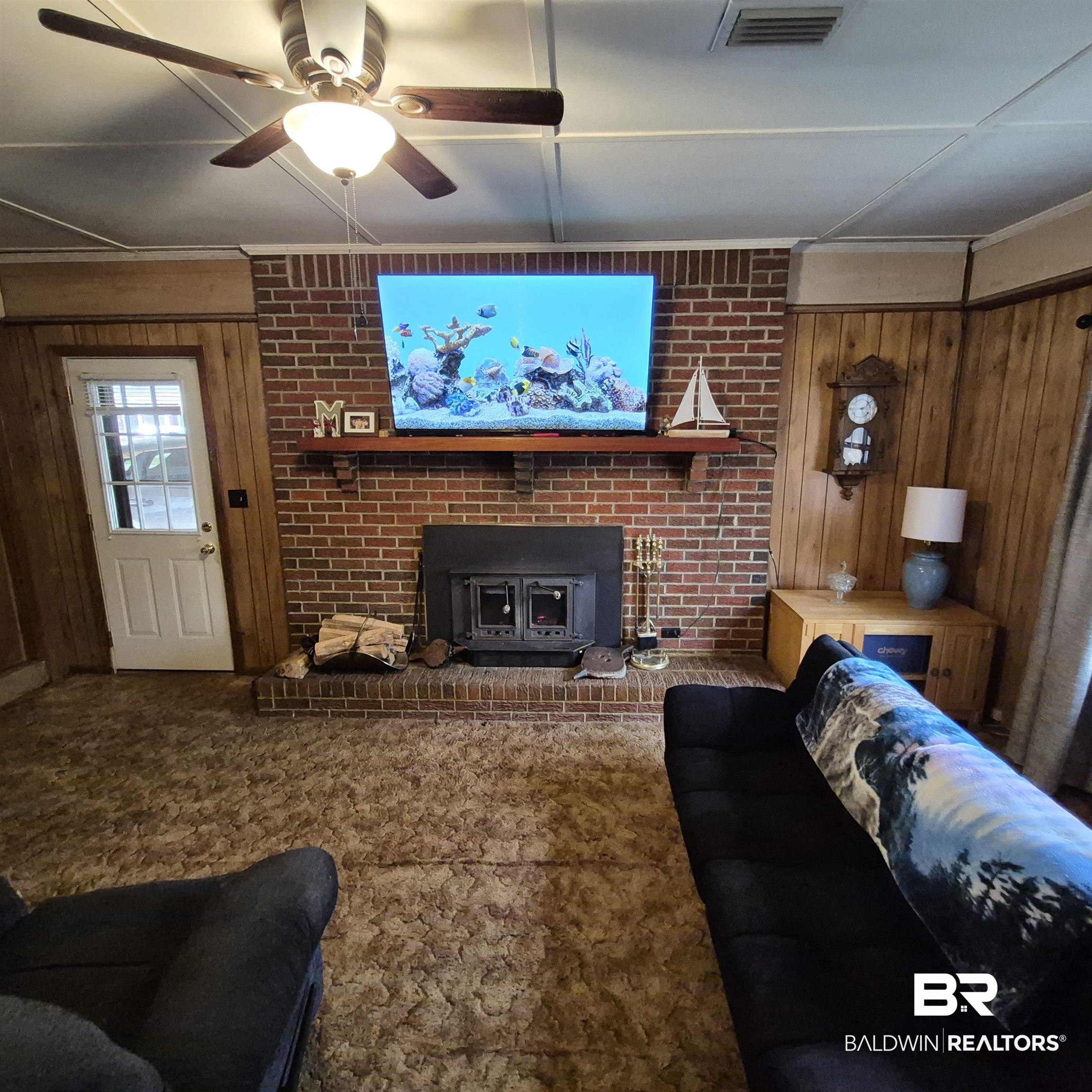 491 Forrest Avenue Castleberry, AL 36432 - Photo 12 of 33 Carpeted living area featuring wooden walls and a ceiling fan