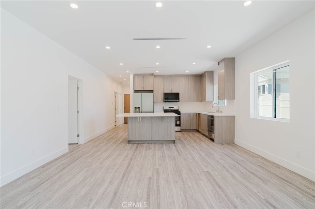 17846 Rinaldi Street Granada Hills, CA 91344 - Photo 11 of 34 a large white kitchen with kitchen island a sink dishwasher a refrigerator and white cabinets with wooden floor