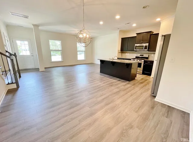a large kitchen with hardwood floor a sink stainless steel appliances and cabinets