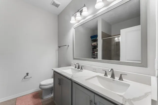 a bathroom with a toilet a sink a mirror and a window