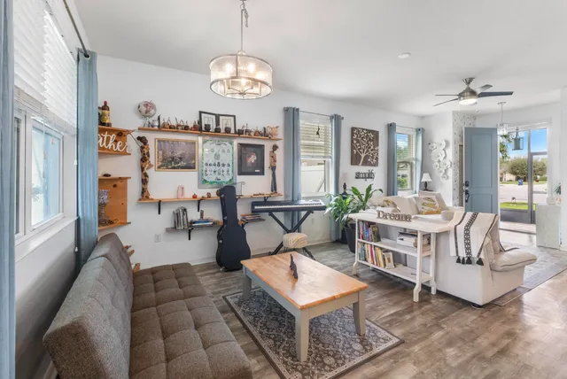 a kitchen with stainless steel appliances granite countertop a refrigerator a sink a stove a dining table and chairs with wooden floor