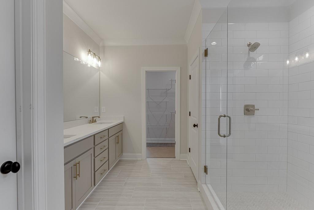173 Swimming Pool Road Buford, GA 30518 - Photo 31 of 35 a bathroom with a double vanity sink a large mirror and shower