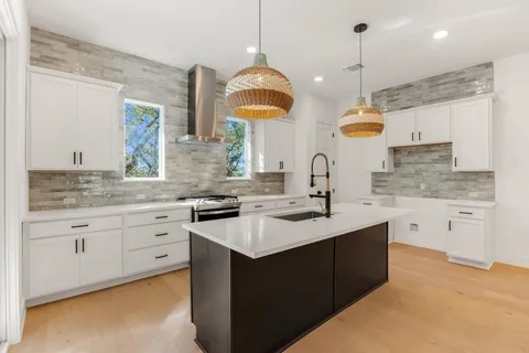 a kitchen with stainless steel appliances granite countertop a sink a stove and a wooden floors
