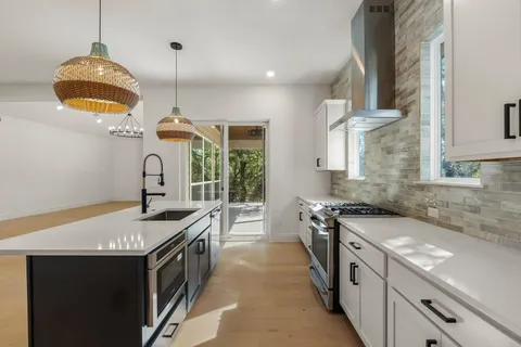 a kitchen with stainless steel appliances granite countertop a stove a sink and a microwave