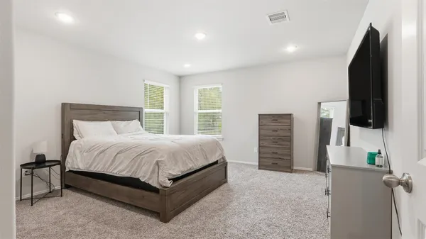 a spacious bedroom with a bed and a flat screen tv