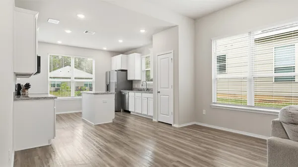 a large kitchen with kitchen island wooden floors white cabinets and stainless steel appliances