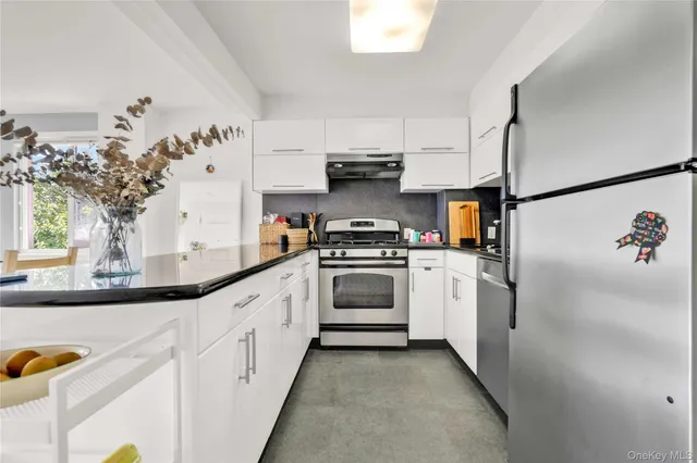 a kitchen with stainless steel appliances a white stove top oven and white cabinets