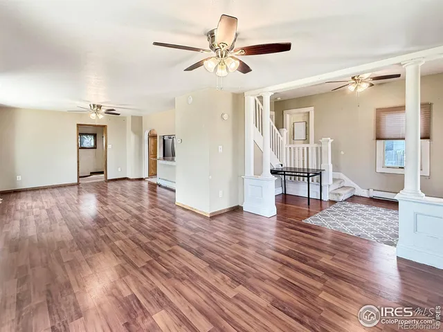 a view of an empty room and wooden floor and a ceiling fan