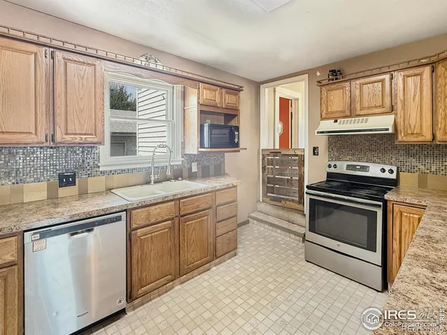 a kitchen with granite countertop a sink stainless steel appliances and cabinets
